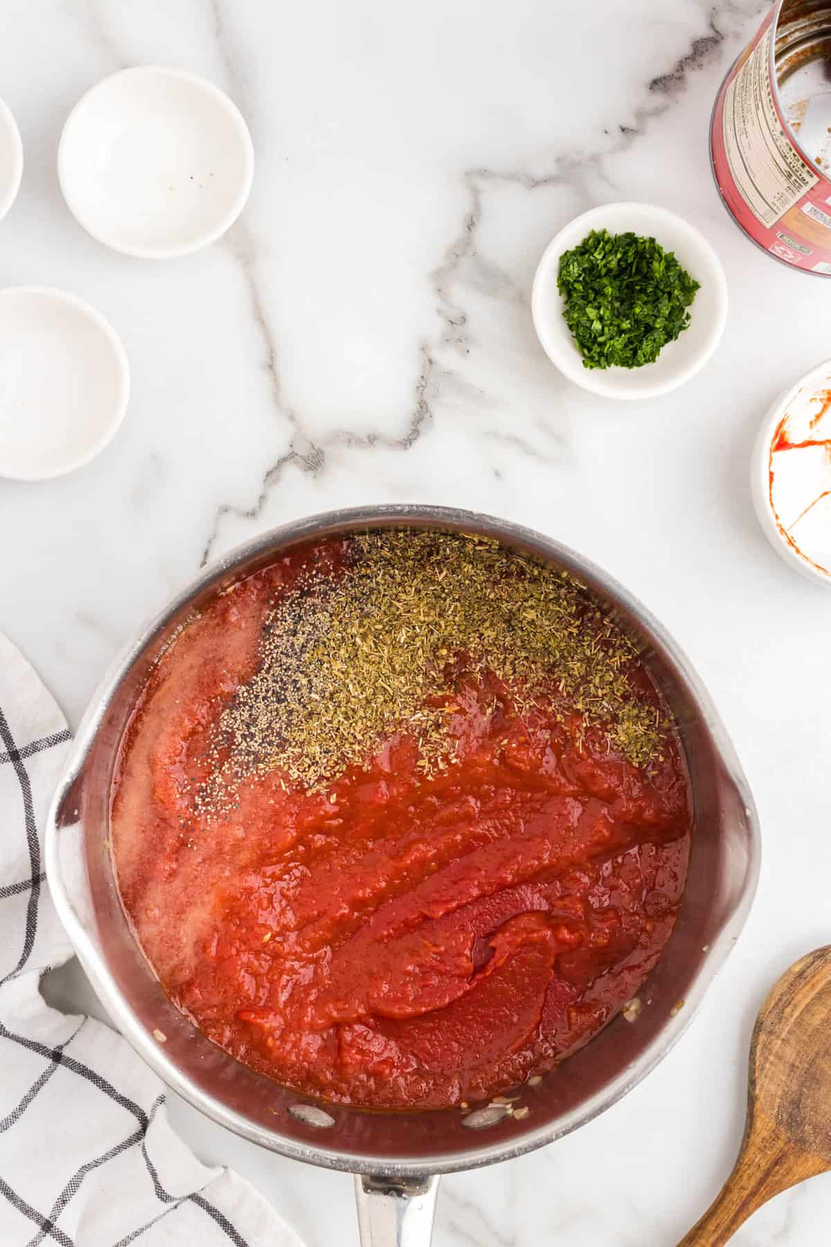 Adding tomatoes and other seasoning to Homemade Marinara Sauce in stovetop pan