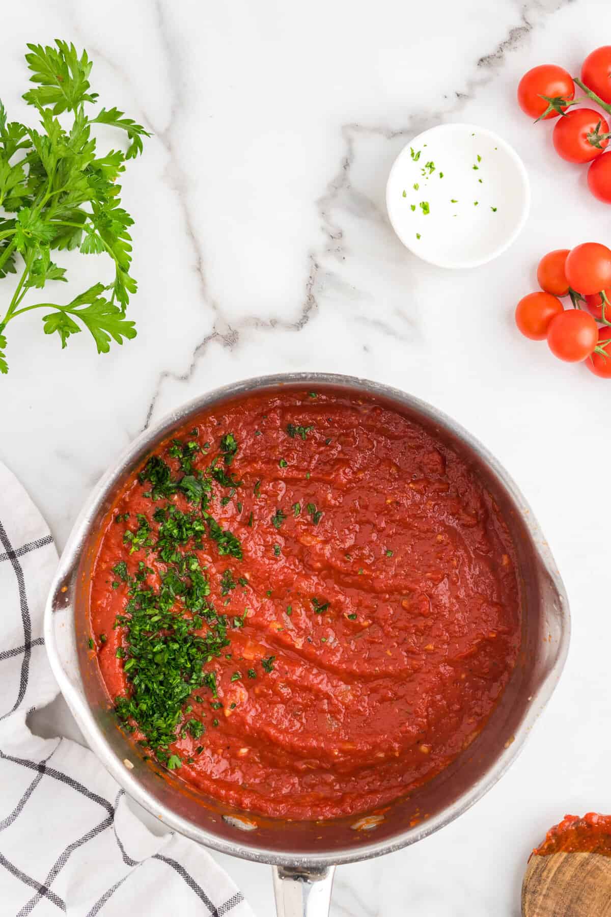 Adding fresh chopped parsley to Homemade Marinara Sauce recipe in stovetop pot