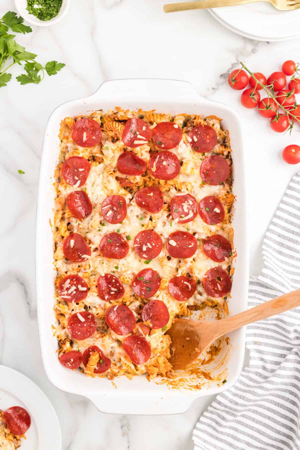 Pizza casserole recipe in 9x13 baking dish with wooden spoon scooping out first bite