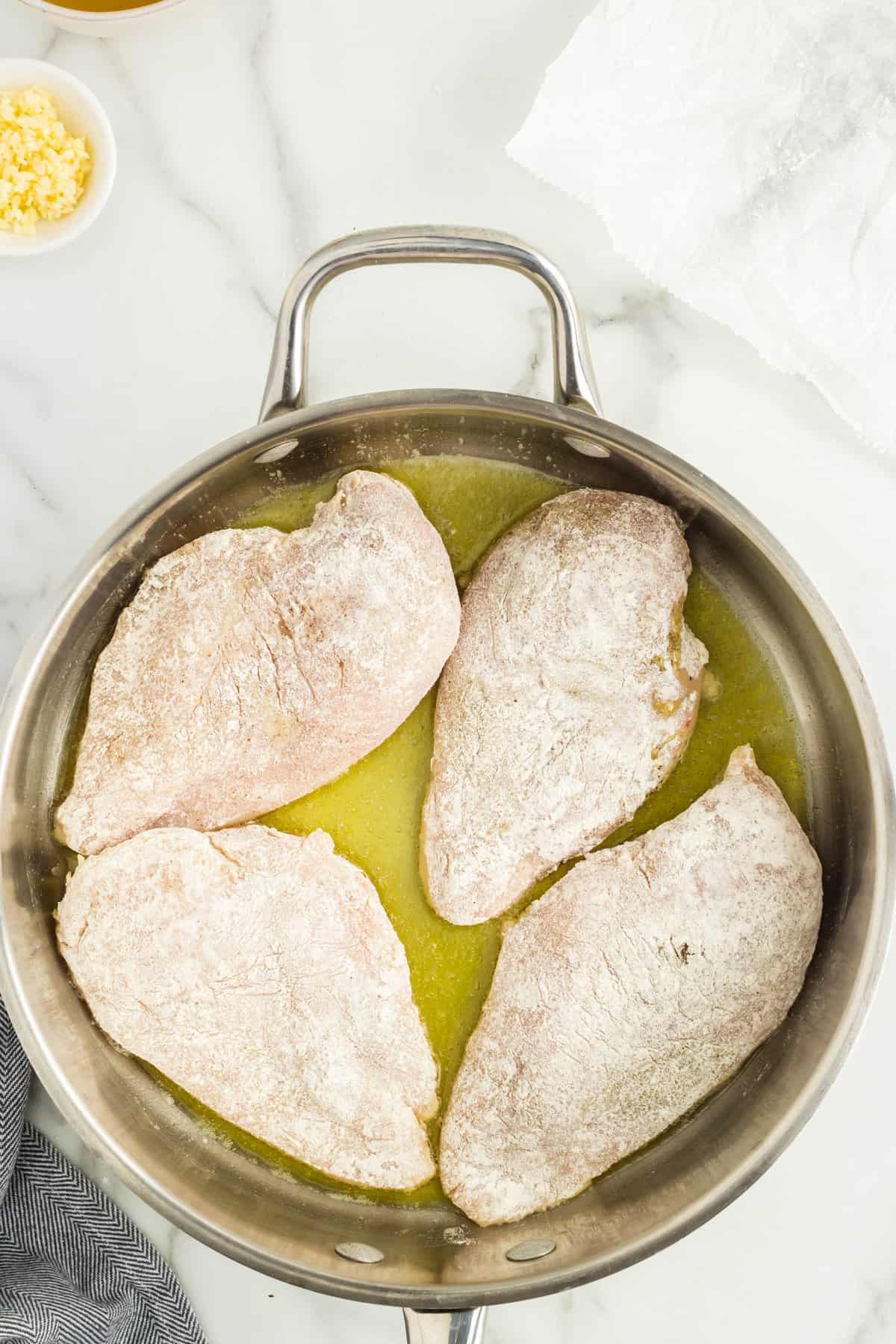 Coated chicken breasts in olive oil in pan for Marry Me Chicken Recipe