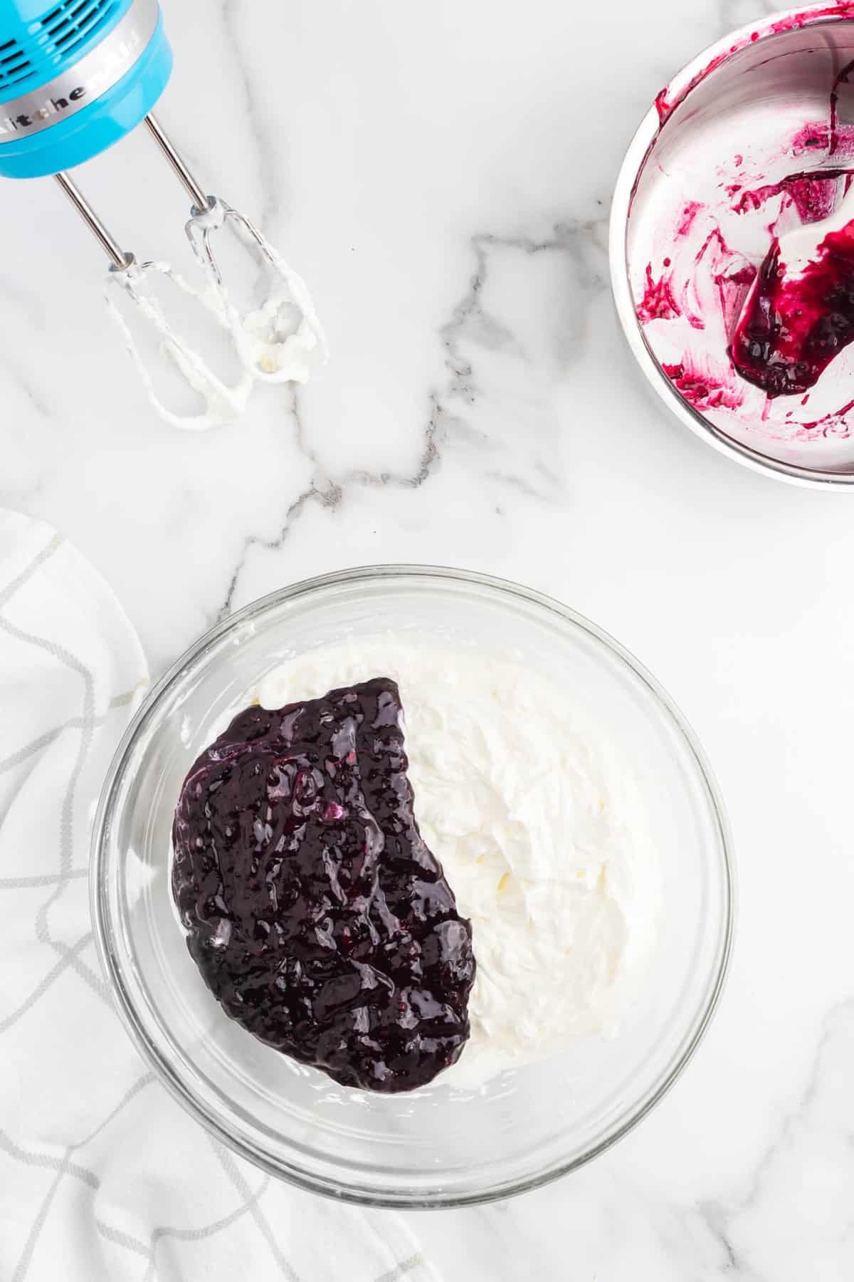 Whipped cream with blueberry mixture in bowl for No Bake Blueberry Cheesecake recipe