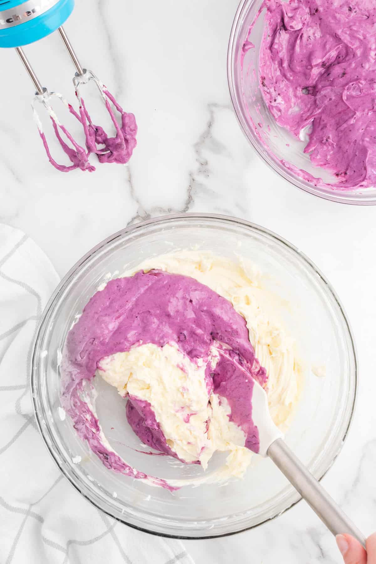 Gently folding blueberry mixture into cream cheese mixture with spatula for No Bake Blueberry Cheesecake recipe