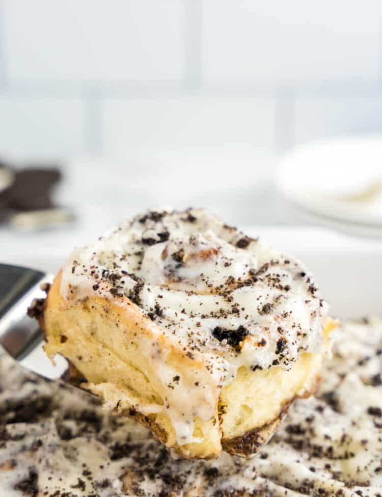 Scooping Homemade Cinnamon Rolls with Oreos out of pan with spatula