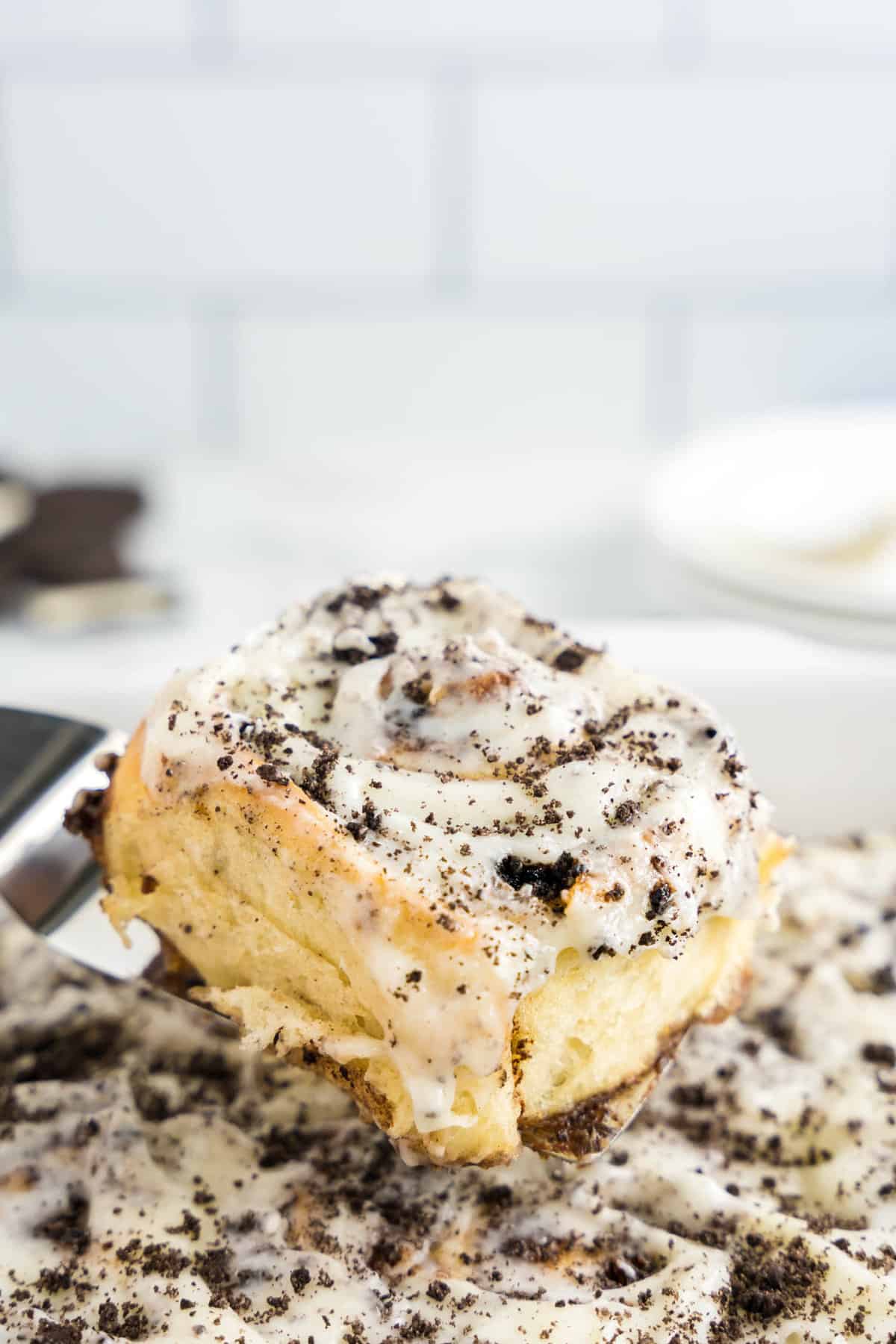 Scooping Homemade Cinnamon Rolls with Oreos out of pan with spatula