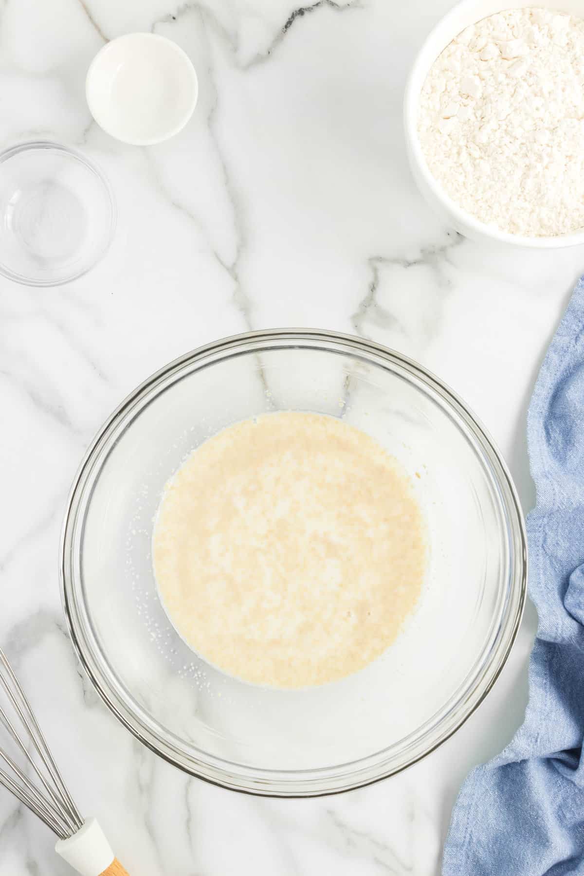 Combining warm milk, sugar, and active yeast in mixing bowl for Oreo Cinnamon Rolls