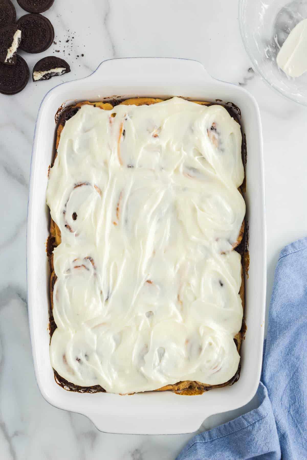 Spreading frosting over Oreo Cinnamon Rolls in Pan