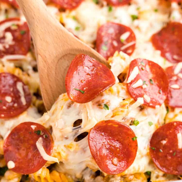 Pizza casserole recipe in baking dish with wooden spoon
