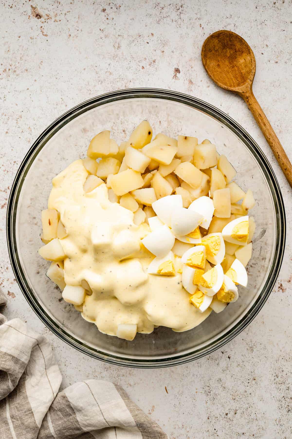 Adding diced hard boiled eggs to potato and dressing mixture for easy homemade potato salad