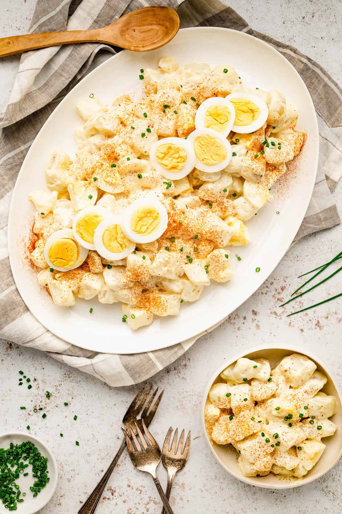 Bowl of potato salad topped with hard boiled egg slices and chives