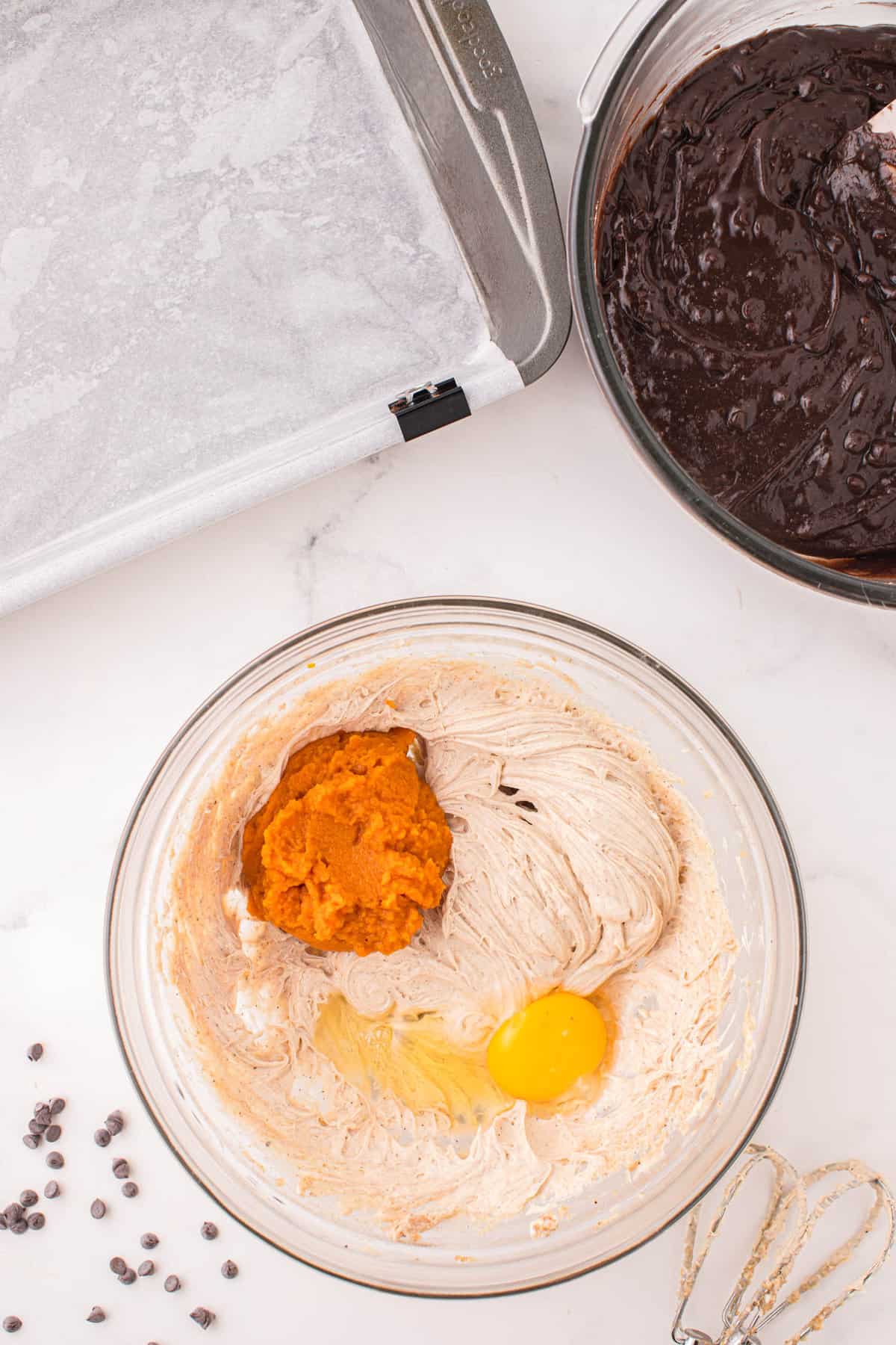 Adding pumpkin and eggs to cream cheese mixture for Pumpkin Brownies recipe in bowl