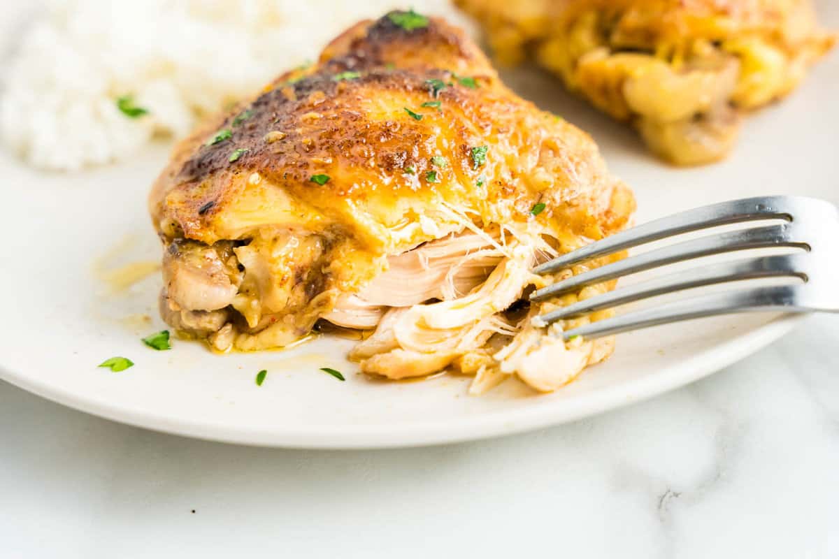Crock Pot Chicken Thighs on Plate with Fork Breaking Apart Thigh