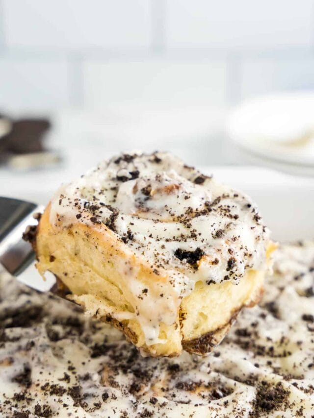Scooping Homemade Cinnamon Rolls with Oreos out of pan with spatula