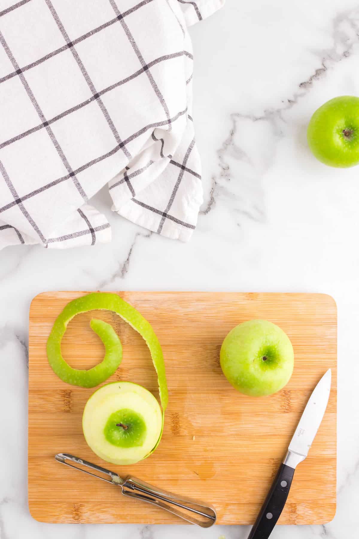 Peeling Granny Smith apples on cutting board for Apple Cinnamon Rolls recipe