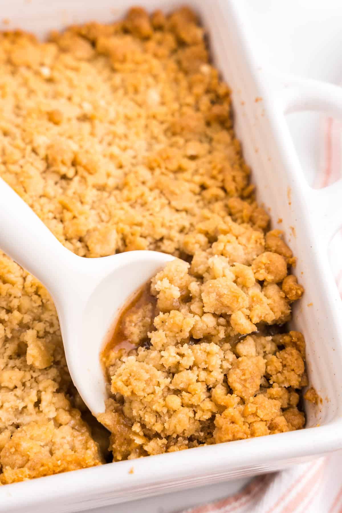 Scooping Apple Crumble from square baking dish