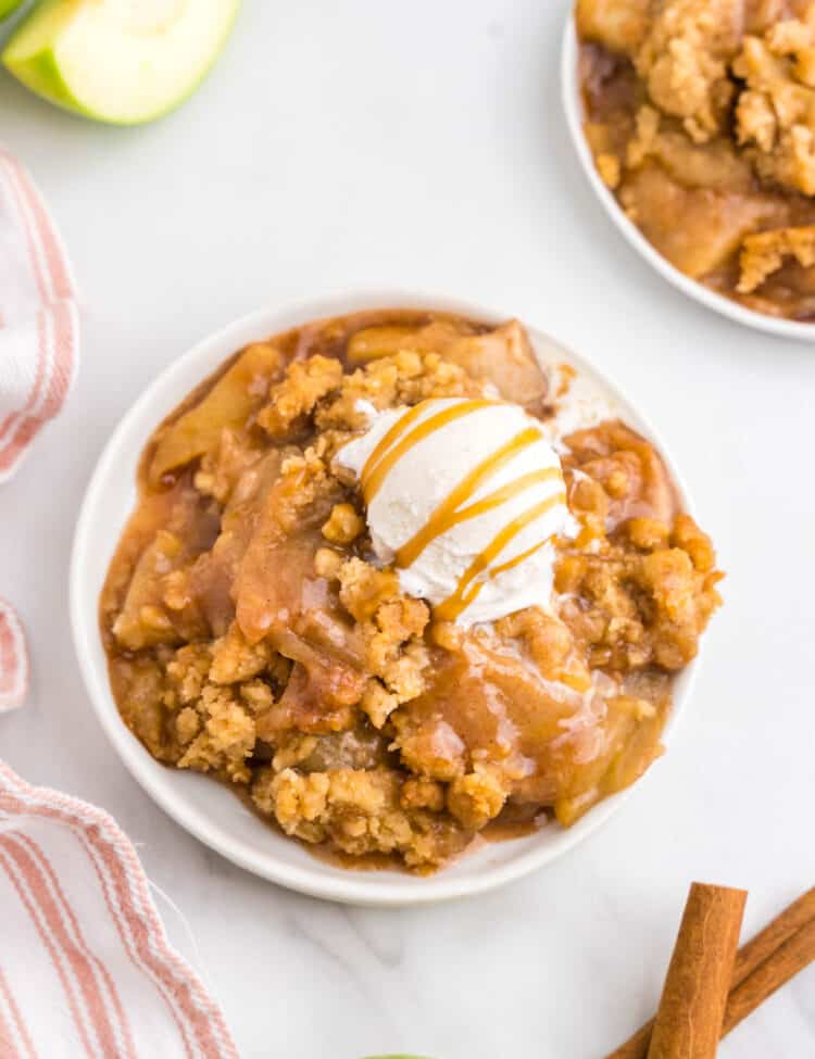 Apple Crumble on plate topped with vanilla ice cream and drizzled caramel