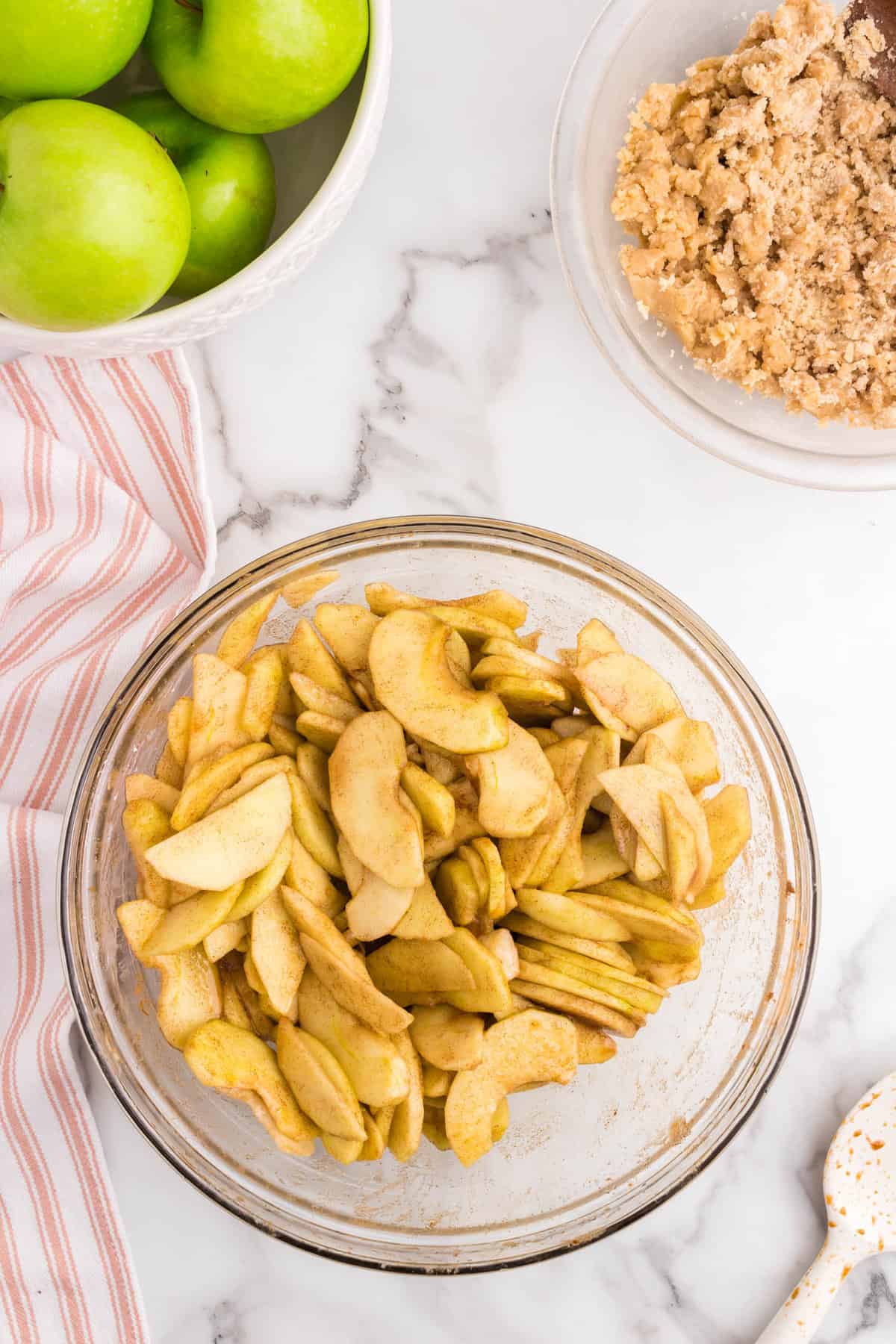 Tossed seasoned apples slices in mixing bowl for Apple Crumble recipe