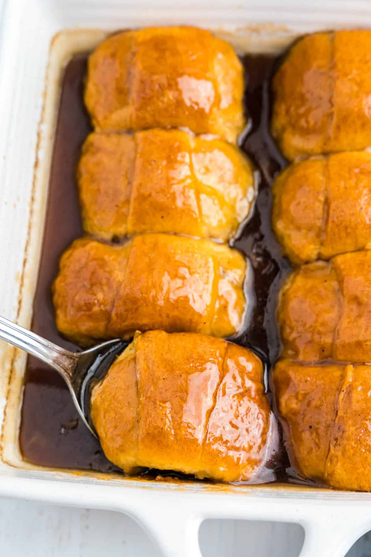 Spoon scooping apple dumpling out of pan