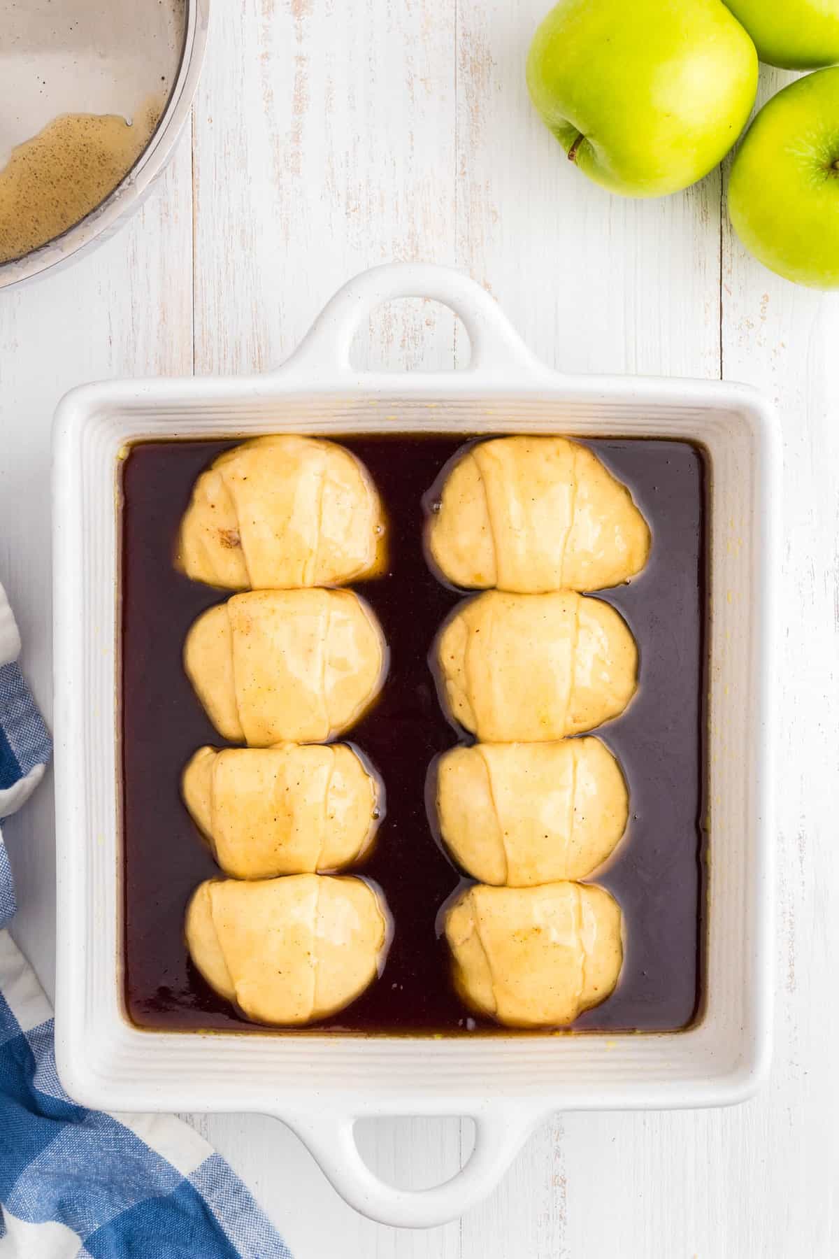 Lining dumplings in sauce coated baking dish for Apple Dumpling recipe