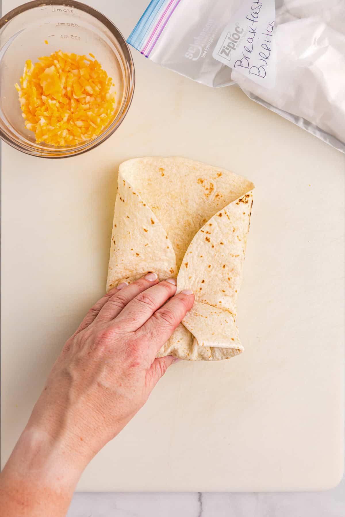 Hand wrapping up breakfast burrito