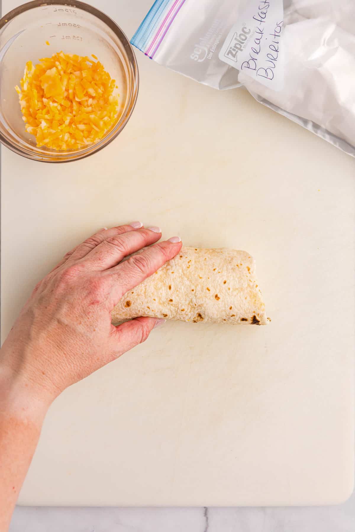 Hand holding breakfast burrito