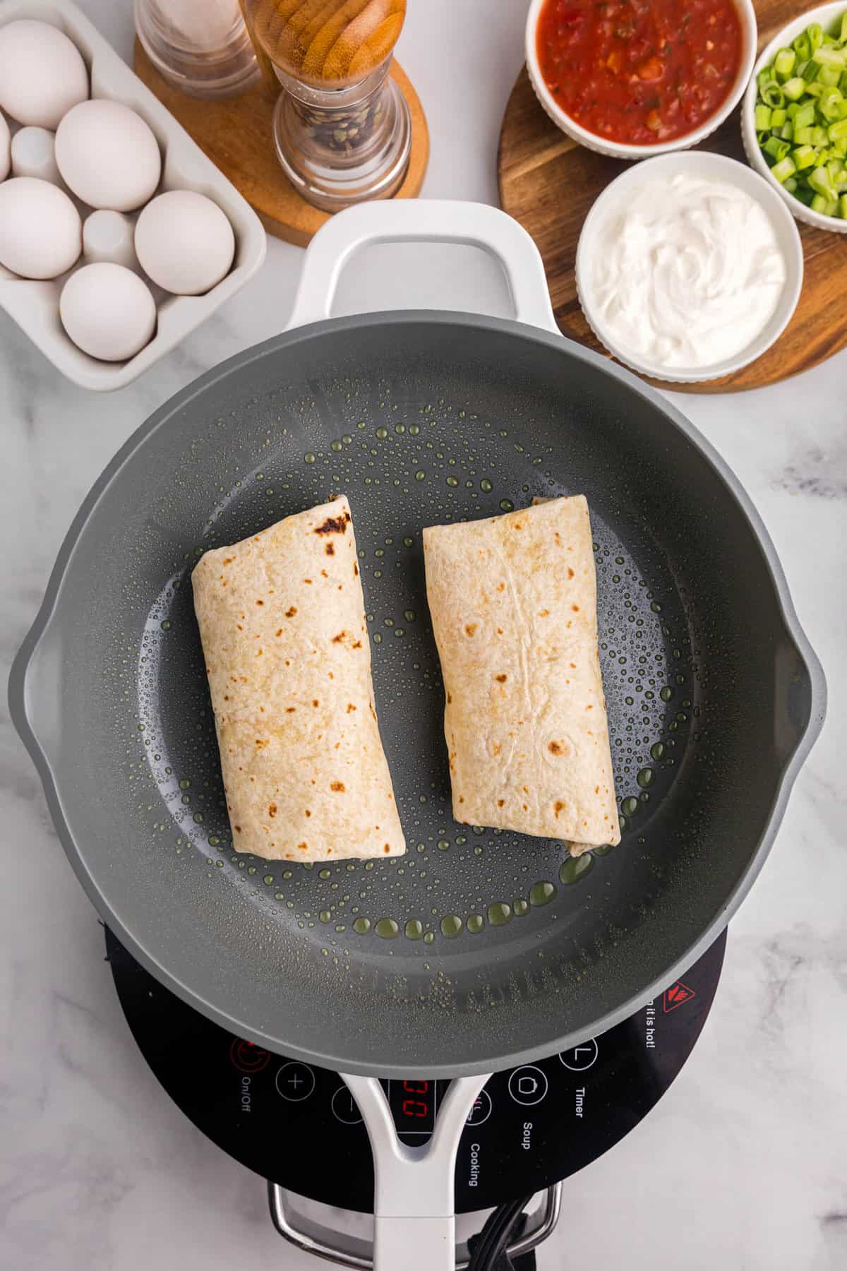 Skillet with breakfast burritos in it