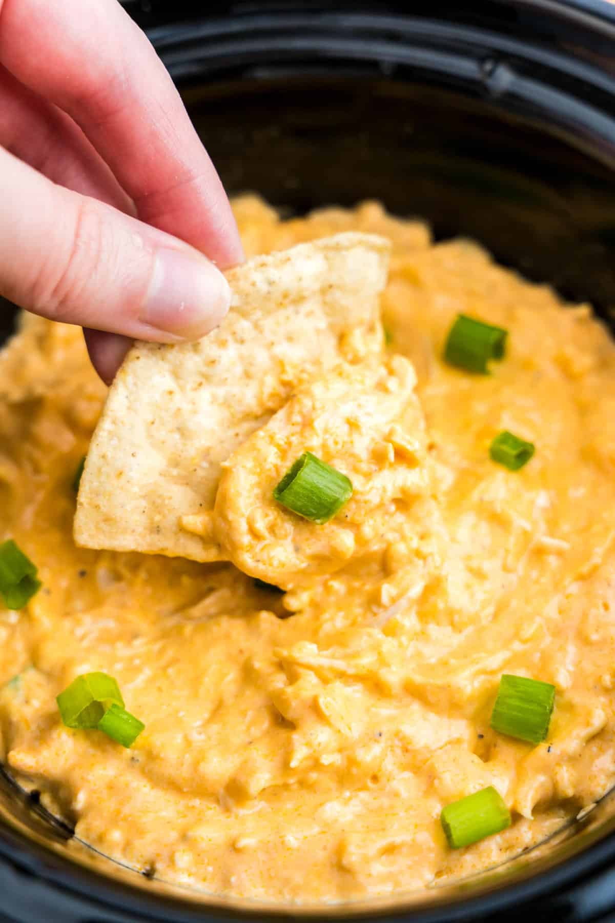 Buffalo Chicken Dip in crock pot with a tortilla chip