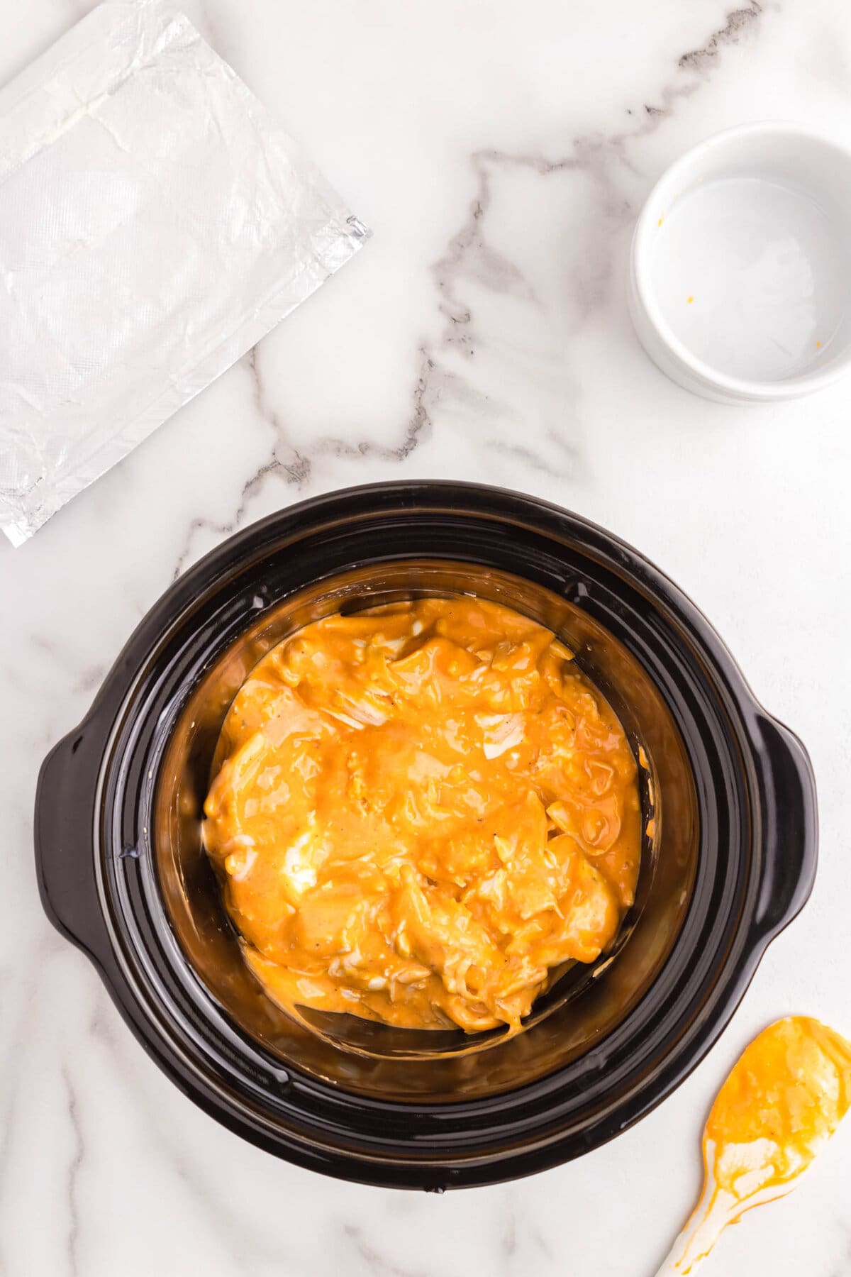 Stirring Buffalo Chicken Dip ingredients in crock pot