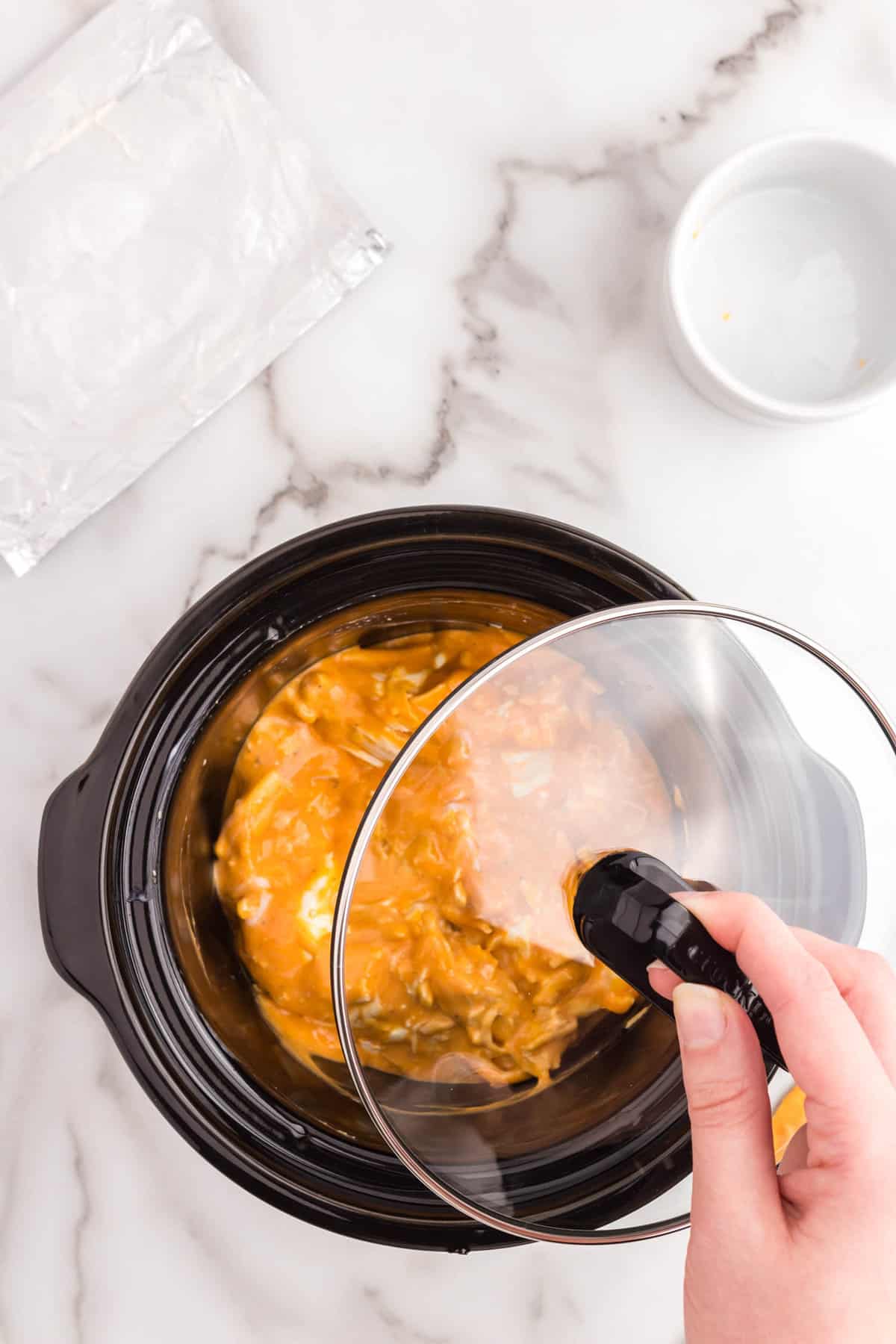 Covering Buffalo Chicken Dip in crock pot for the perfect party appetizer