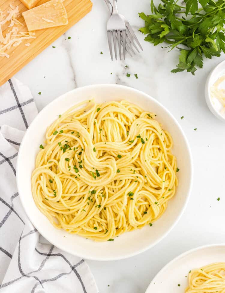 a white bowl full of buttered noodles.