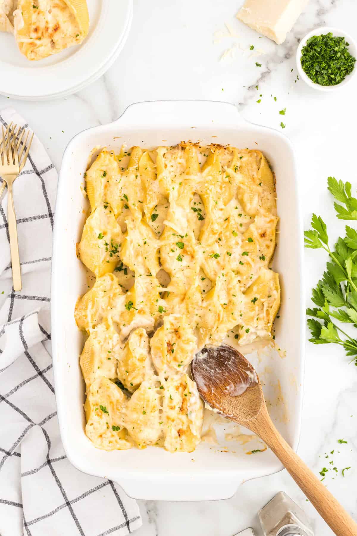 Chicken Alfredo Stuffed Shells in baking dish with wooden spoon