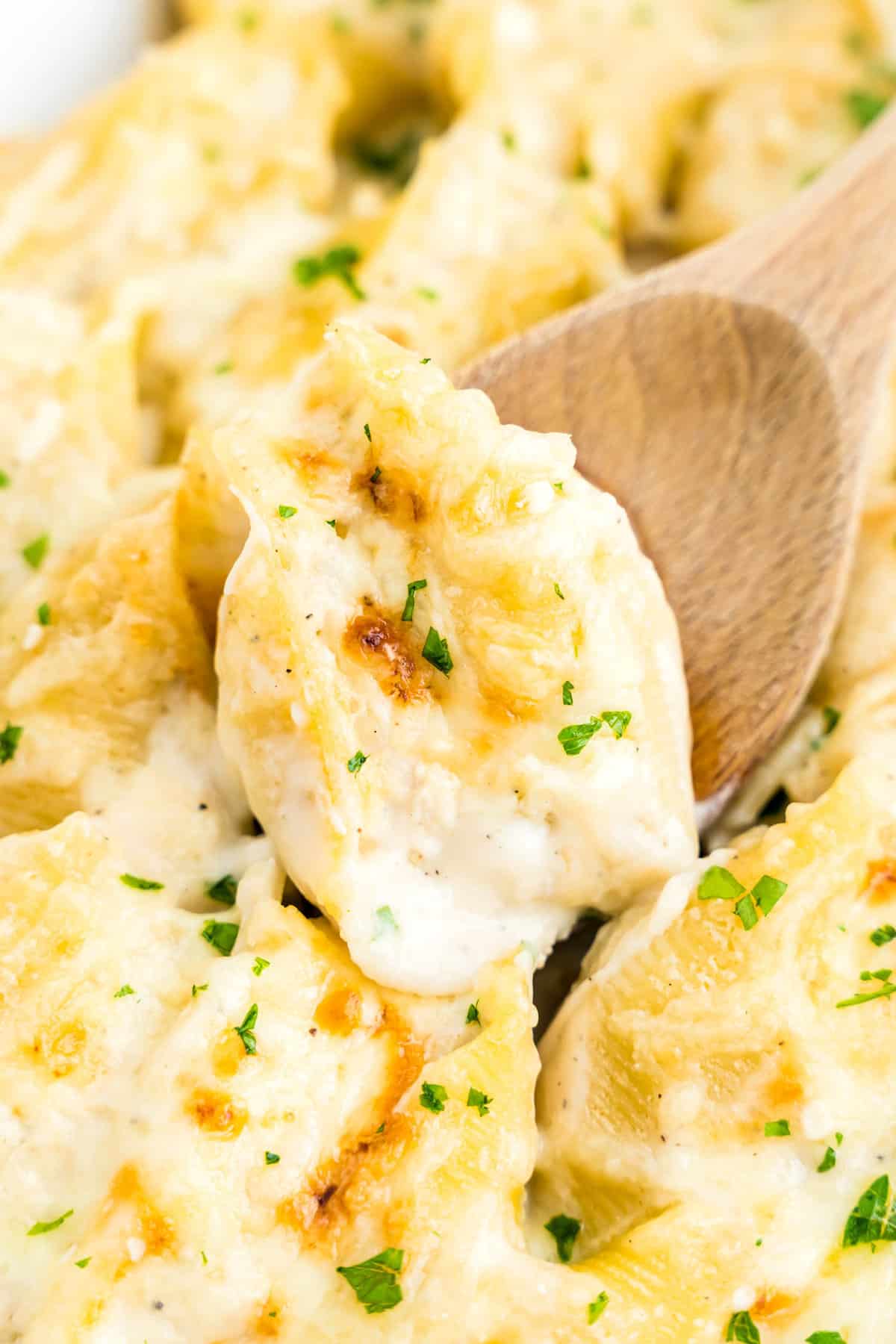 Spoon scooping Chicken Alfredo Stuffed Shells 