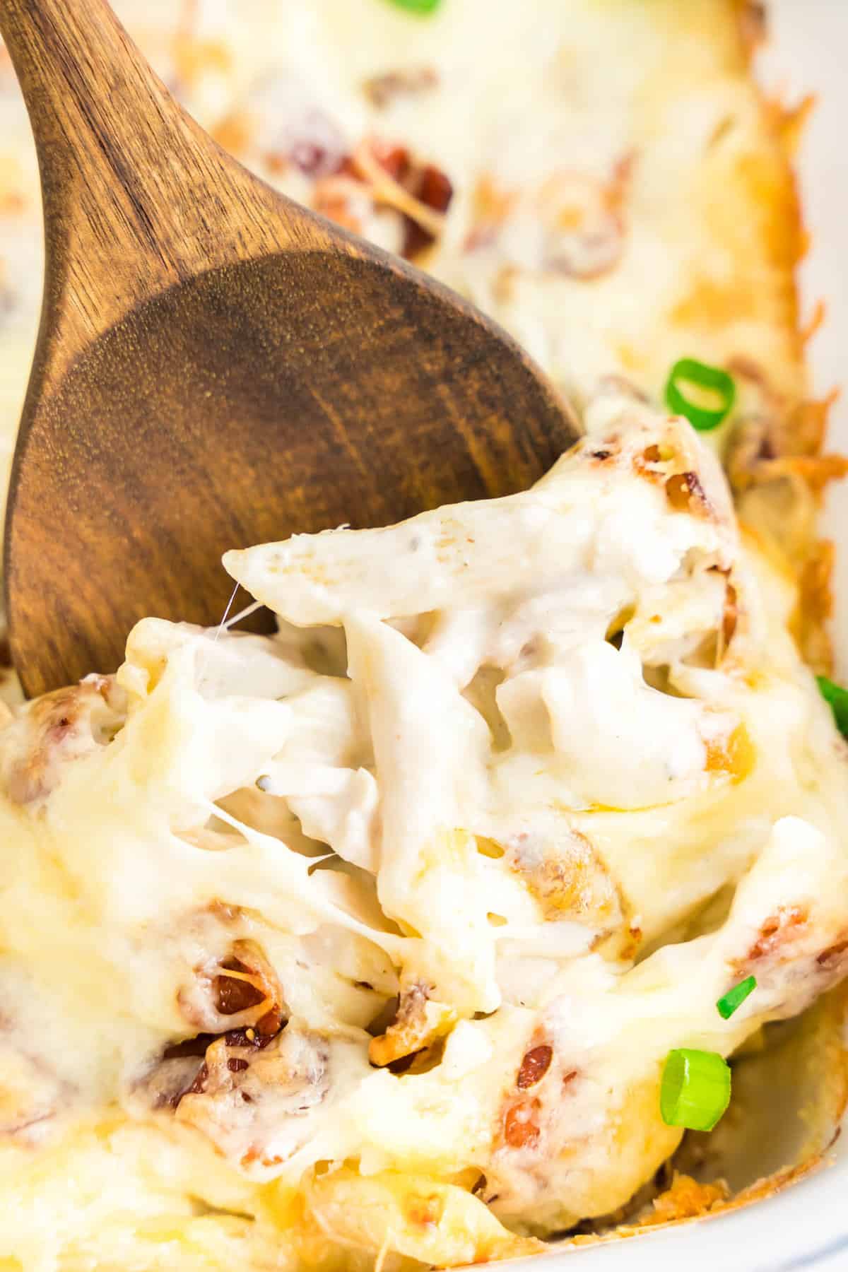 Chicken Bacon Ranch Pasta Bake in Baking Dish with Wooden Spoon Scooping