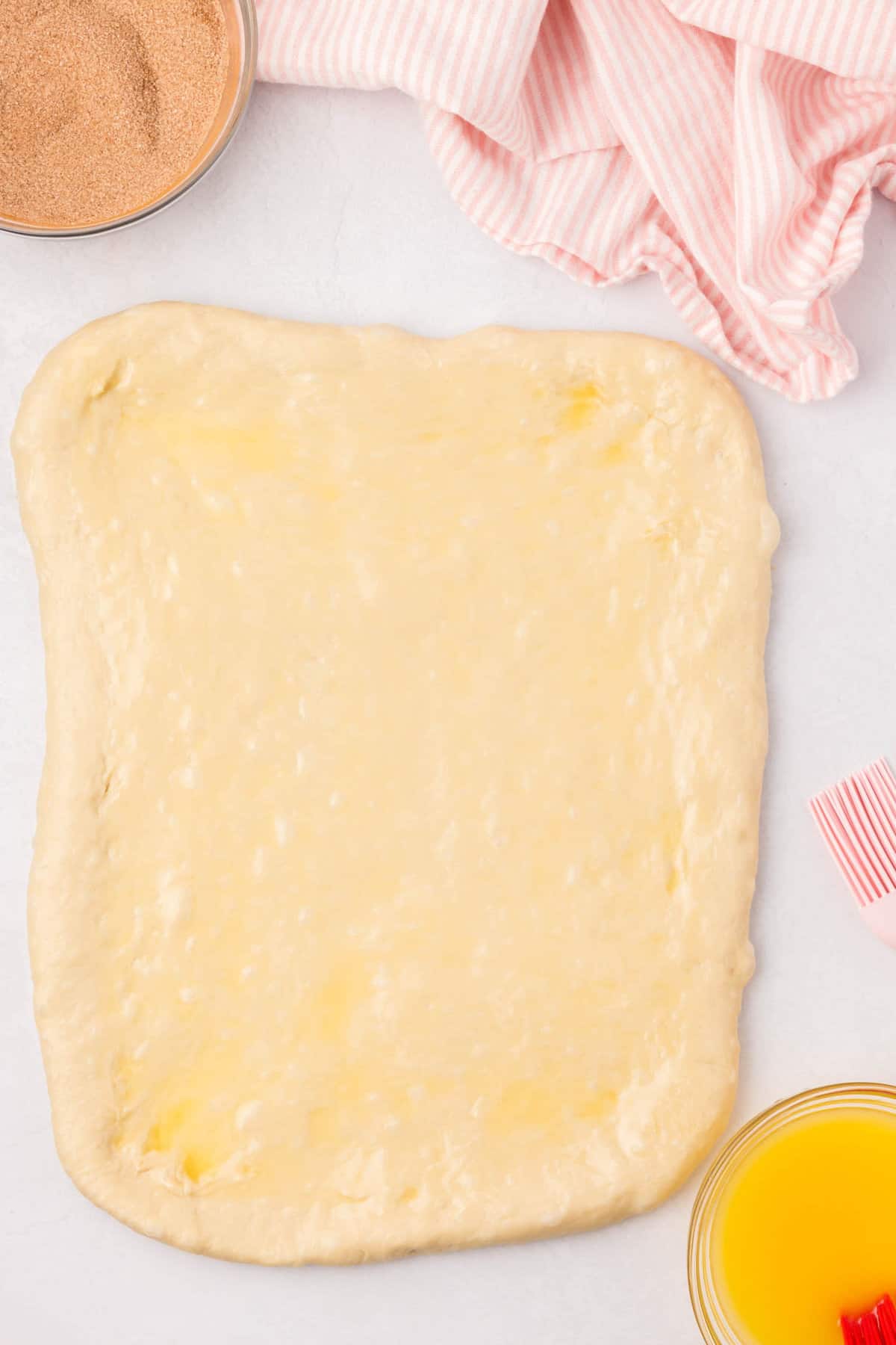 Coating rolled out dough ball with melted butter for Cinnamon Swirl Bread