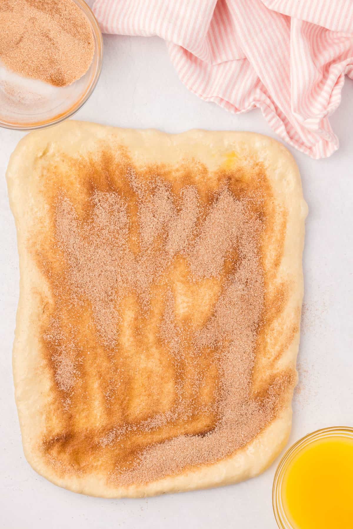 Topping buttered rolled out dough ball with cinnamon sugar mixture for Cinnamon Swirl Bread