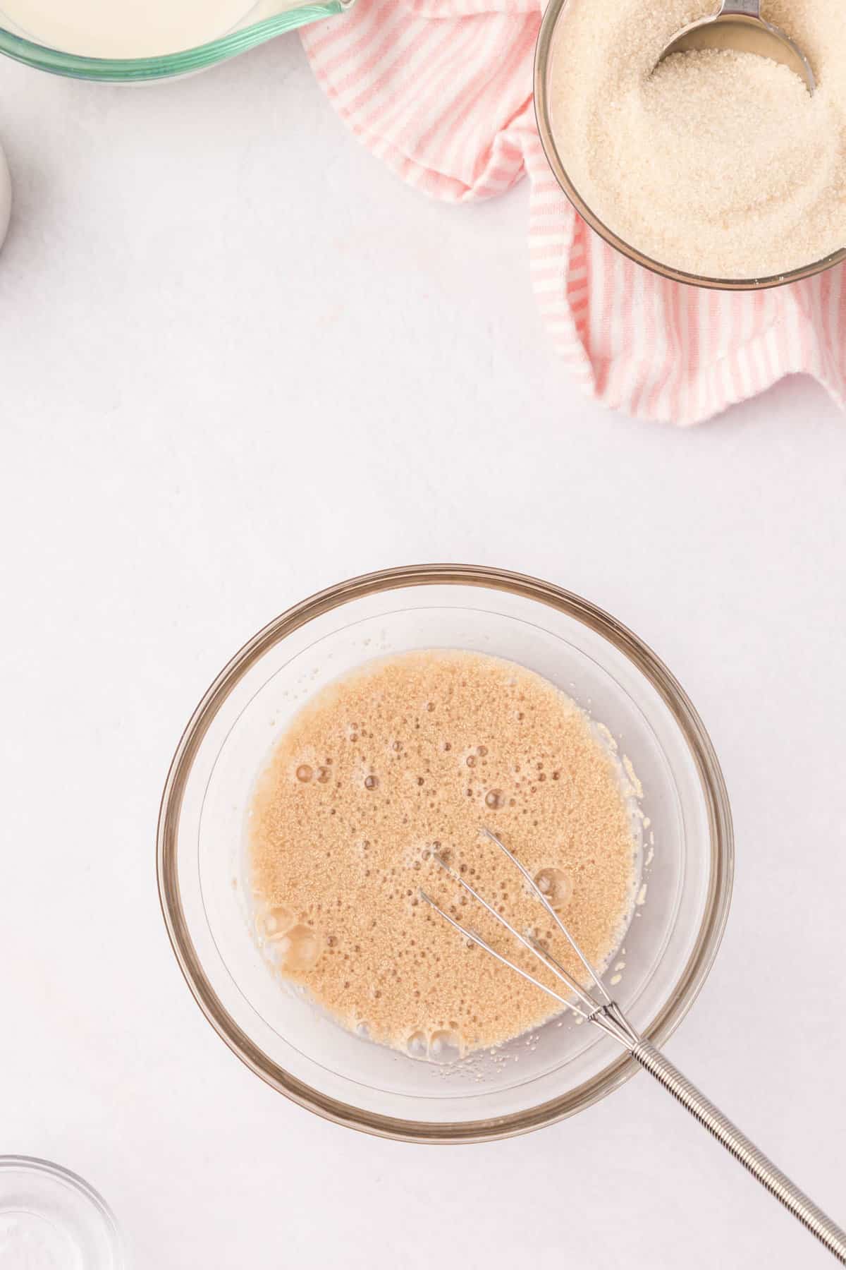 Whisking warm water, active dry yeast, and sugar in small mixing bowl for Cinnamon Swirl Bread