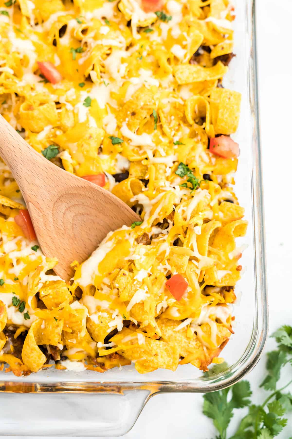 Using wooden scoop for the first taste of Frito Pie Casserole with added toppings