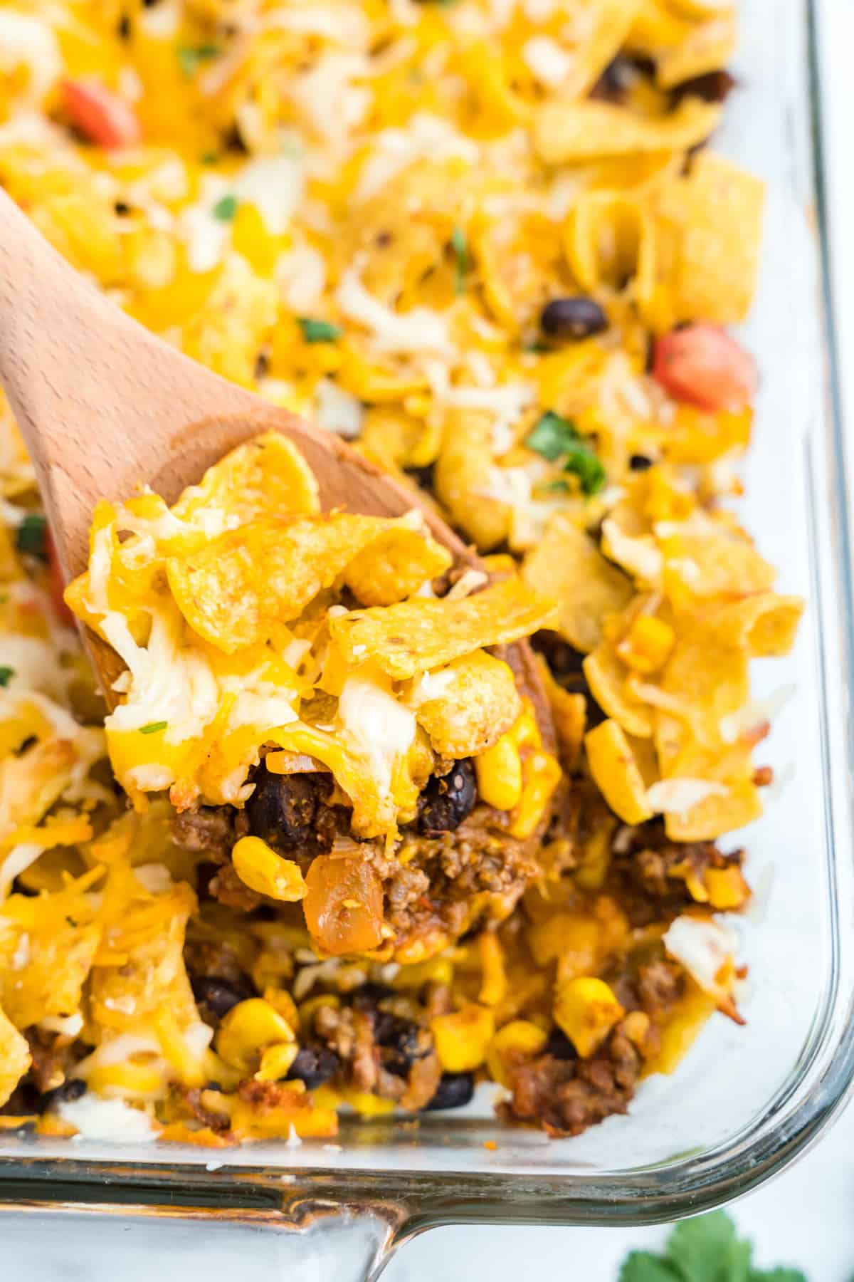 Fritto Pie Casserole in Baking Dish with a Wooden Spoon Dishing the First Scoop