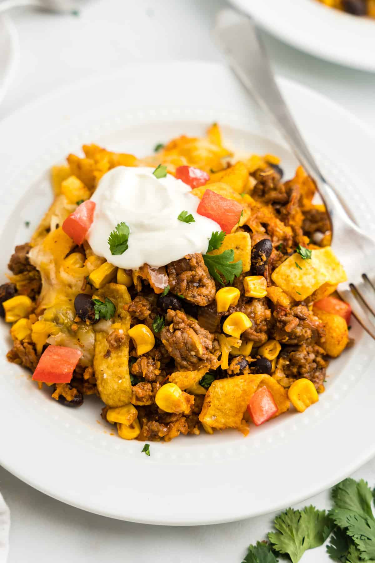 Adding sour cream, green onion, and tomato for an additional flavor burst to Frito Pie Casserole