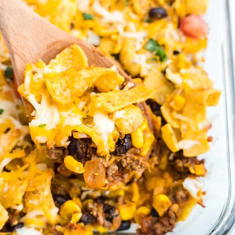 Frito Pie Casserole in Baking Dish with Wooden Spoon Scooping First Bite