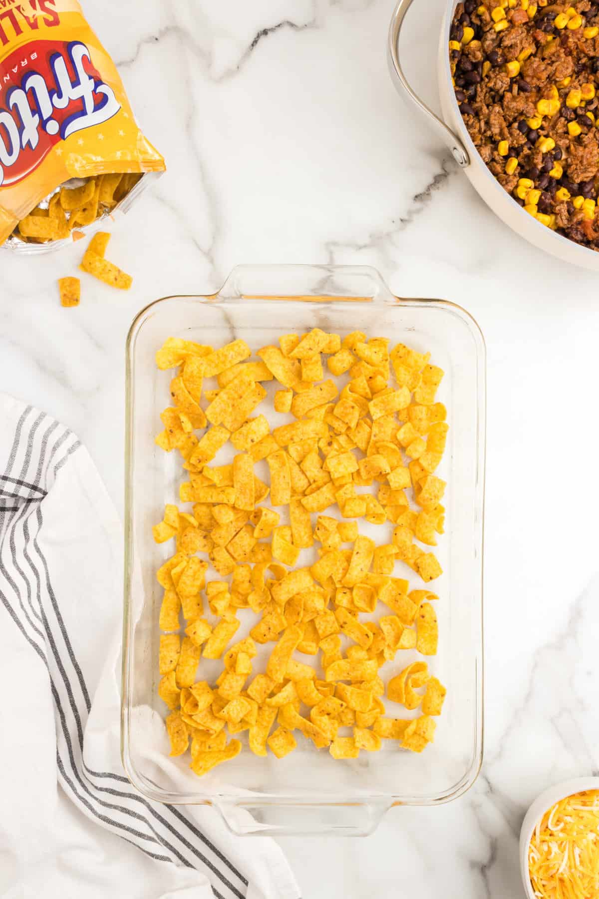 Lining clear baking dish with Fritos for Frito Pie Casserole