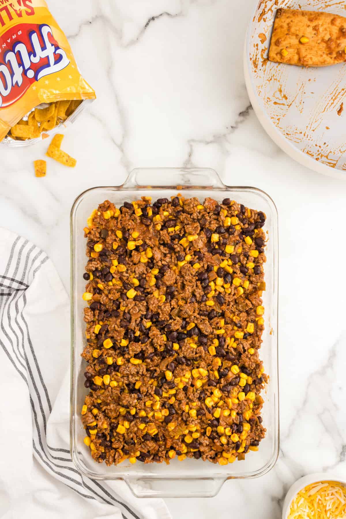 Adding seasoned ground beef, corn, bean, and salsa mixture as another layer of Frito Pie Casserole