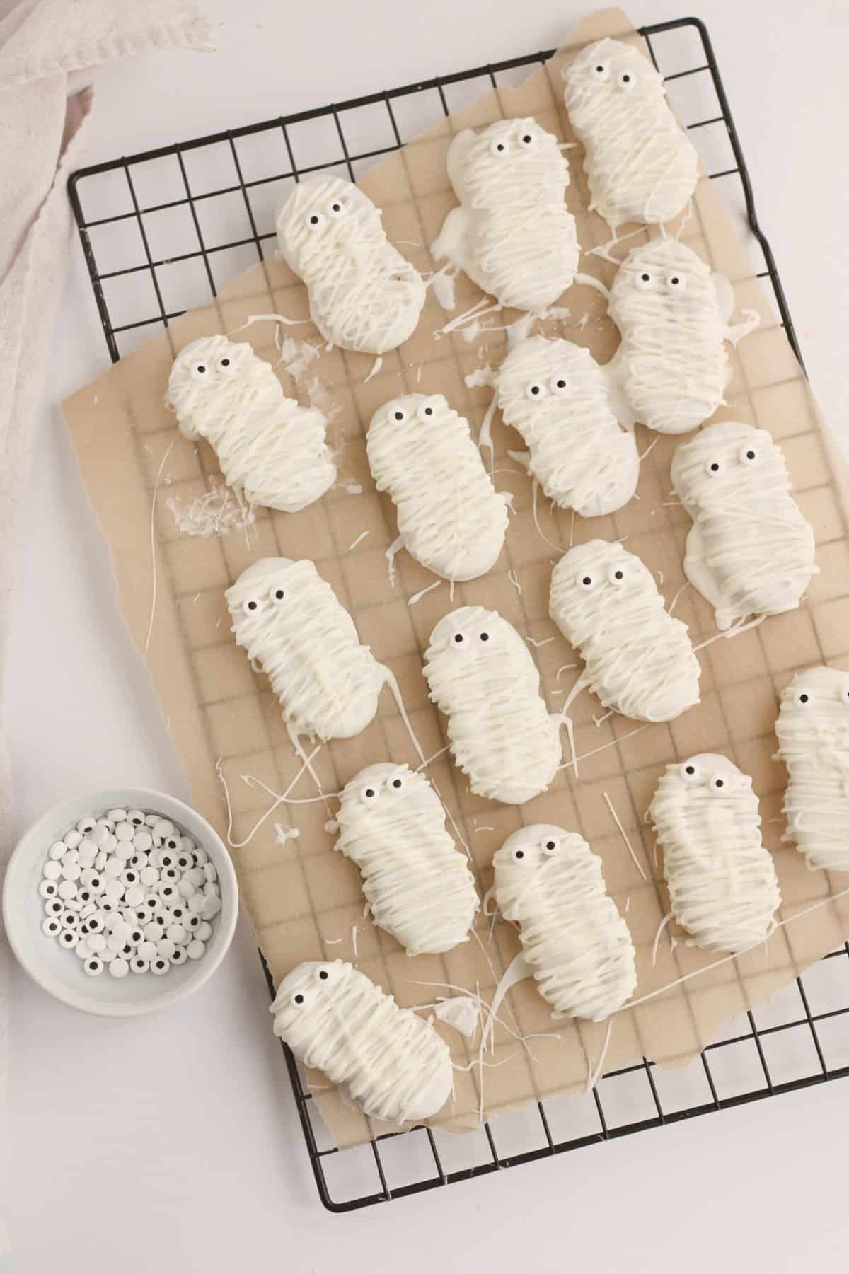 Pipe the white chocolate over the cookies to make it look like a mummy. Add two Googly eyes at the top of the nutter butter for eyes.