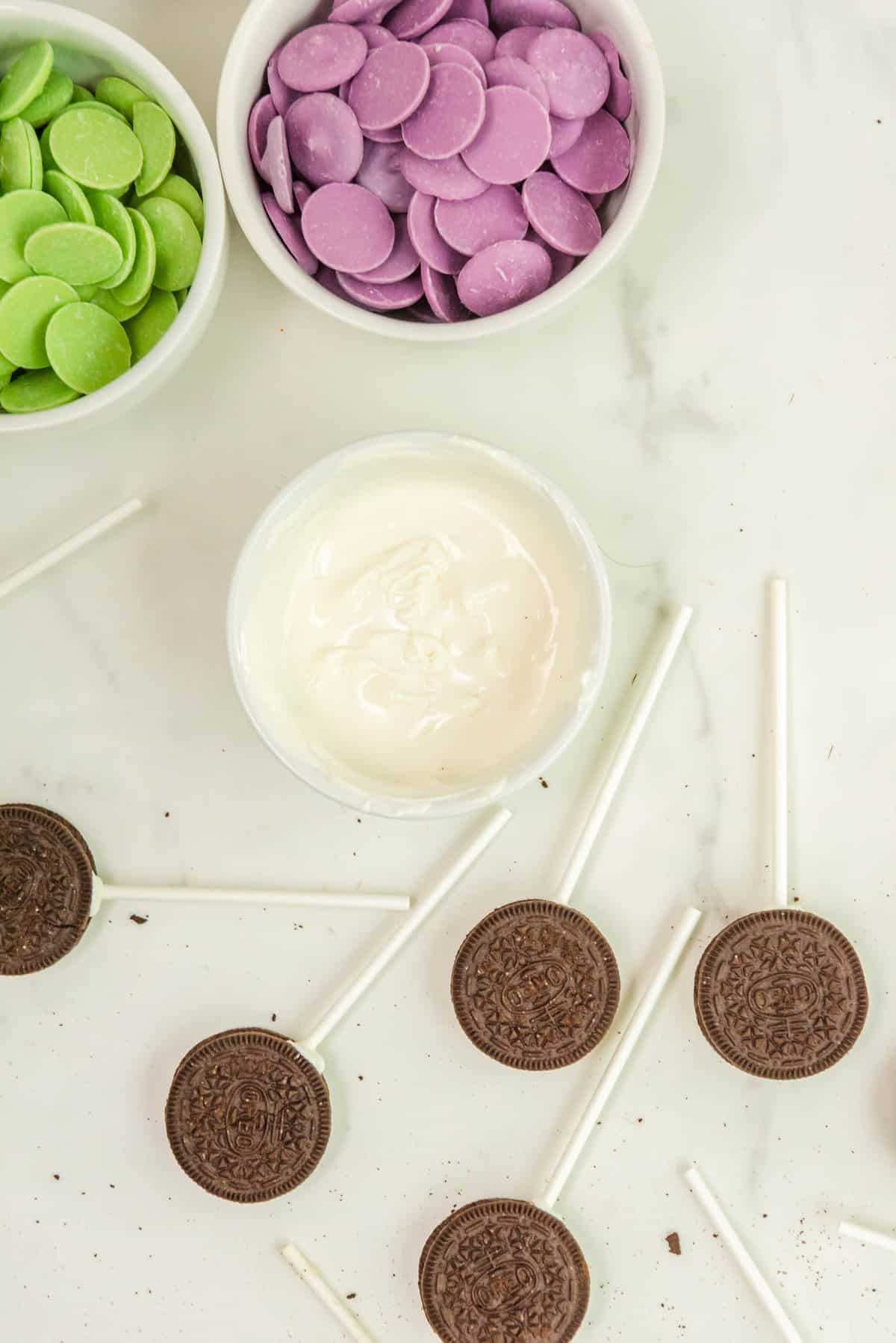 Put the Tips of the Cake Pop Sticks in the Melted White Wafer Melt and stick them into the Oreo Holes. Let these set