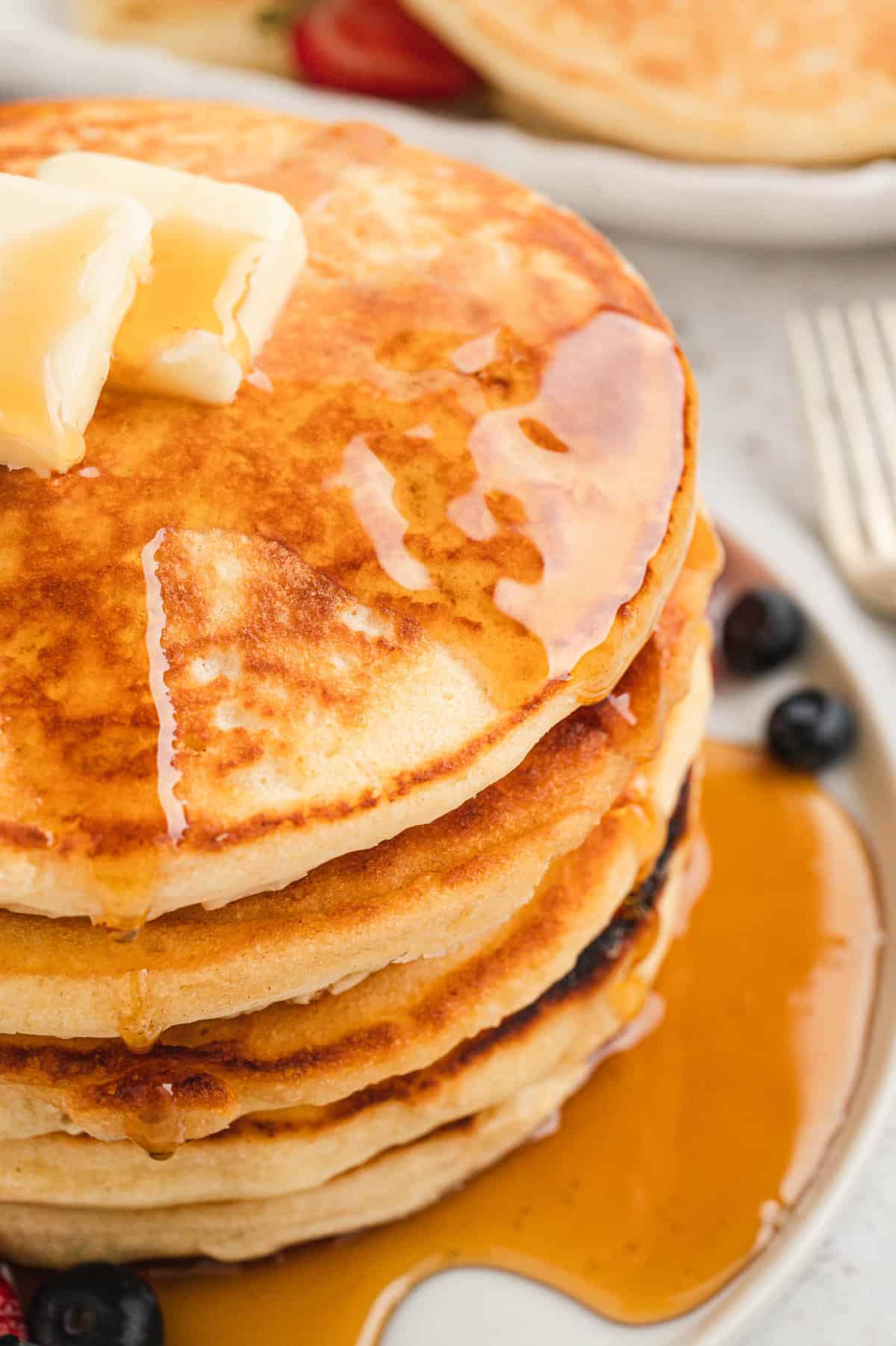 Homemade Pancakes stacked on plate with butter and syrup