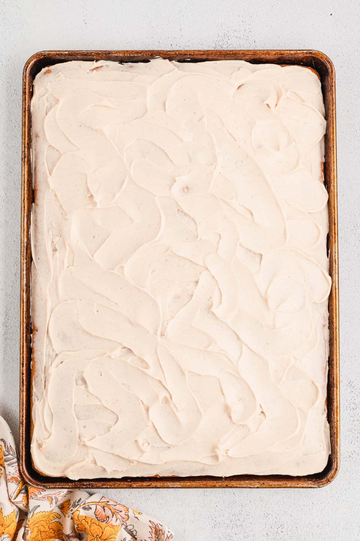 Evenly spreading cream cheese frosting on pumpkin bars in bar for Pumpkin Bars recipe