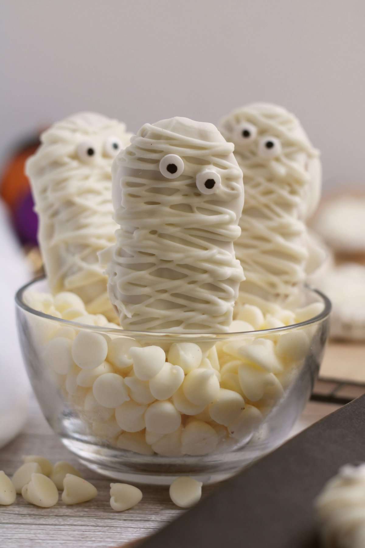 Mummy Cookies standing in a bowl filled with chocolate chips.