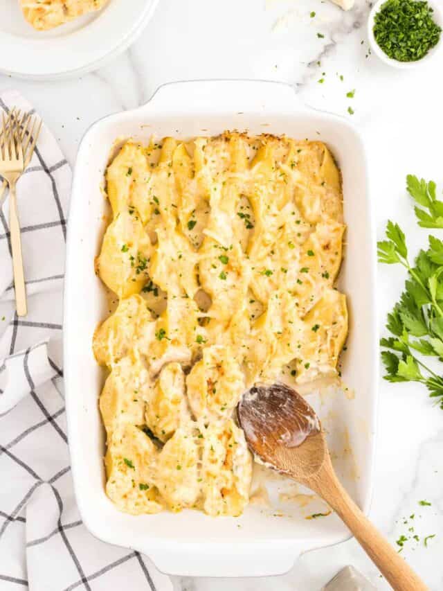 Chicken Alfredo Stuffed Shells in baking dish with wooden spoon