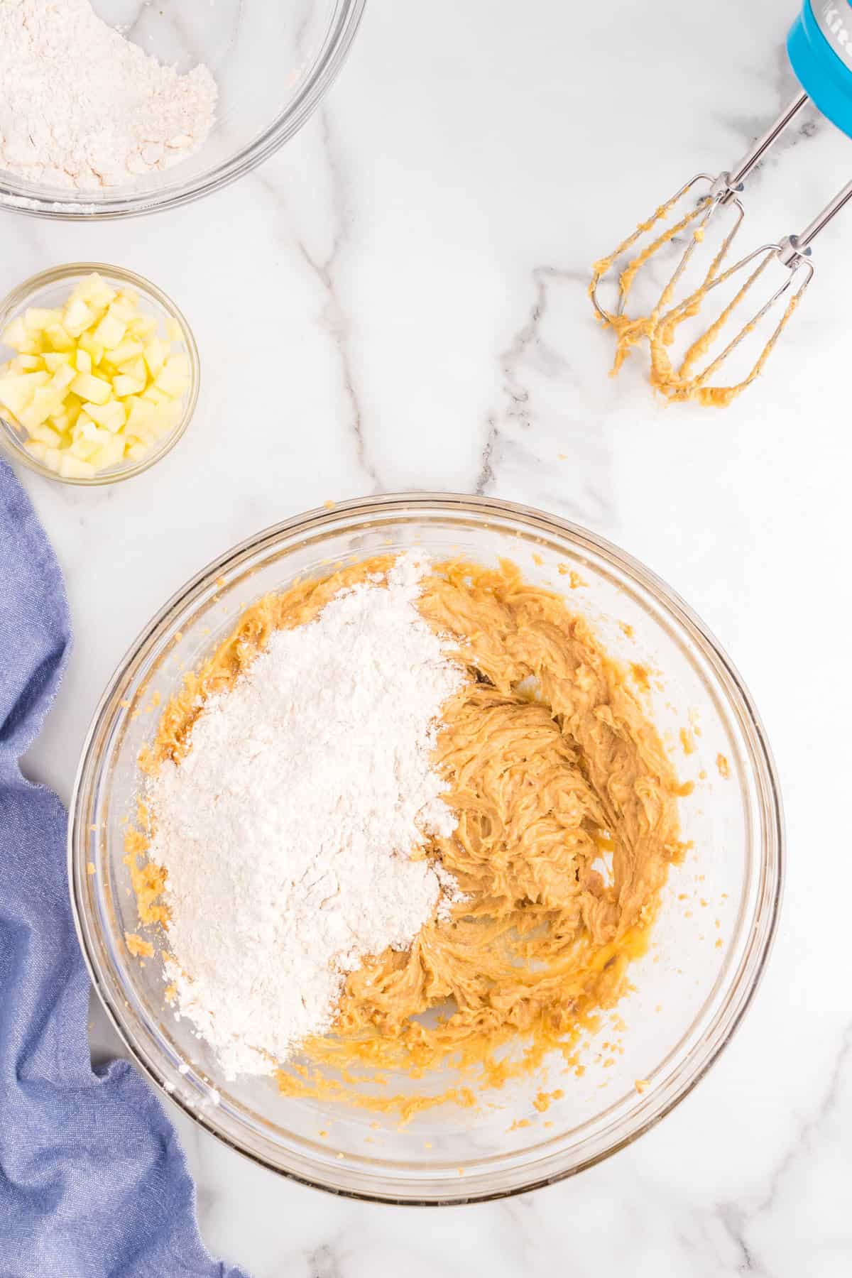 Adding flour to dough mixture for Peanut Butter and Apple Cookies
