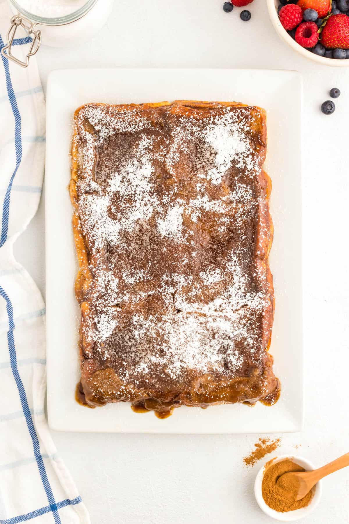 Sifting powdered sugar atop Overnight French Toast on serving platter