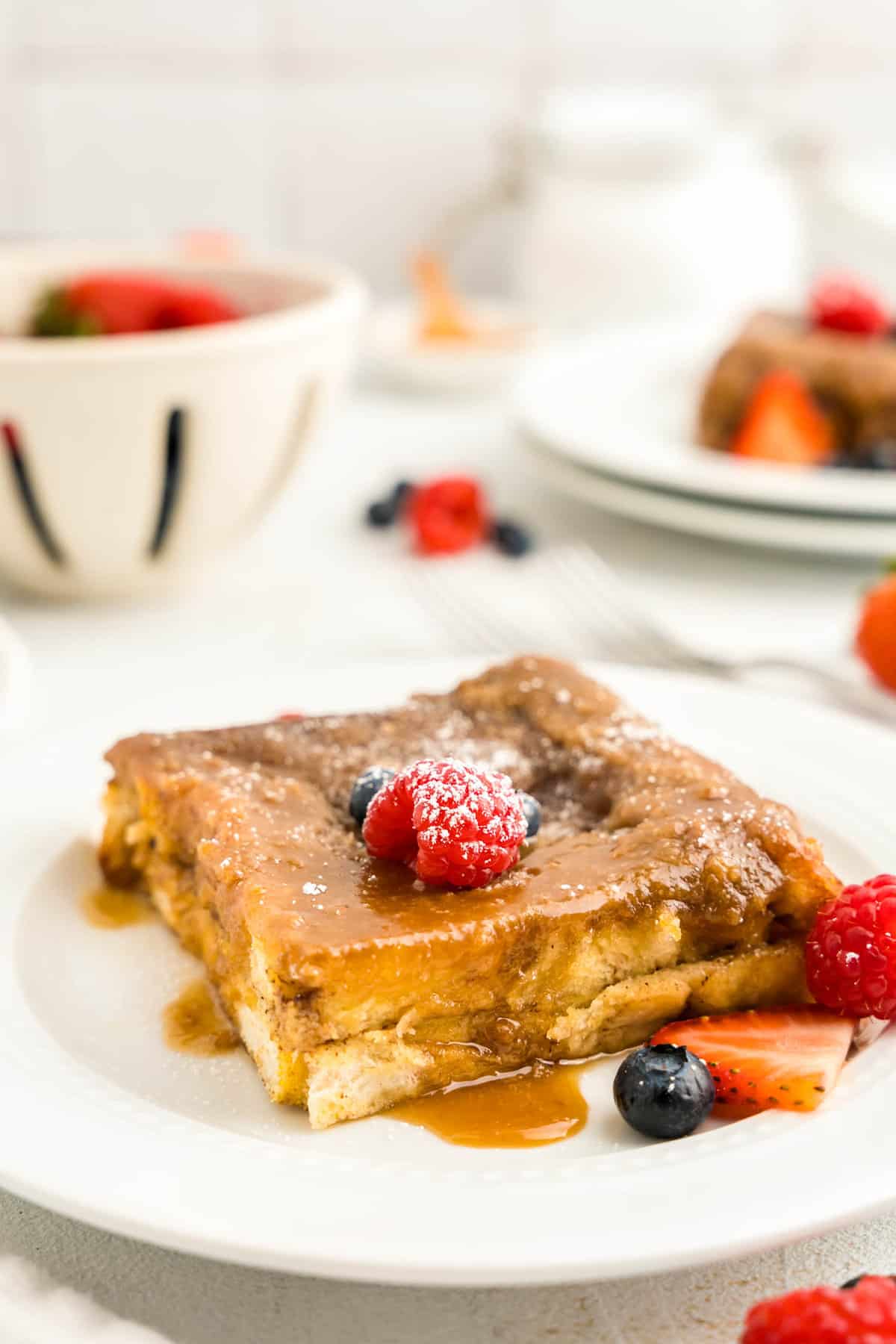 Baked French Toast on white plate with berries on top